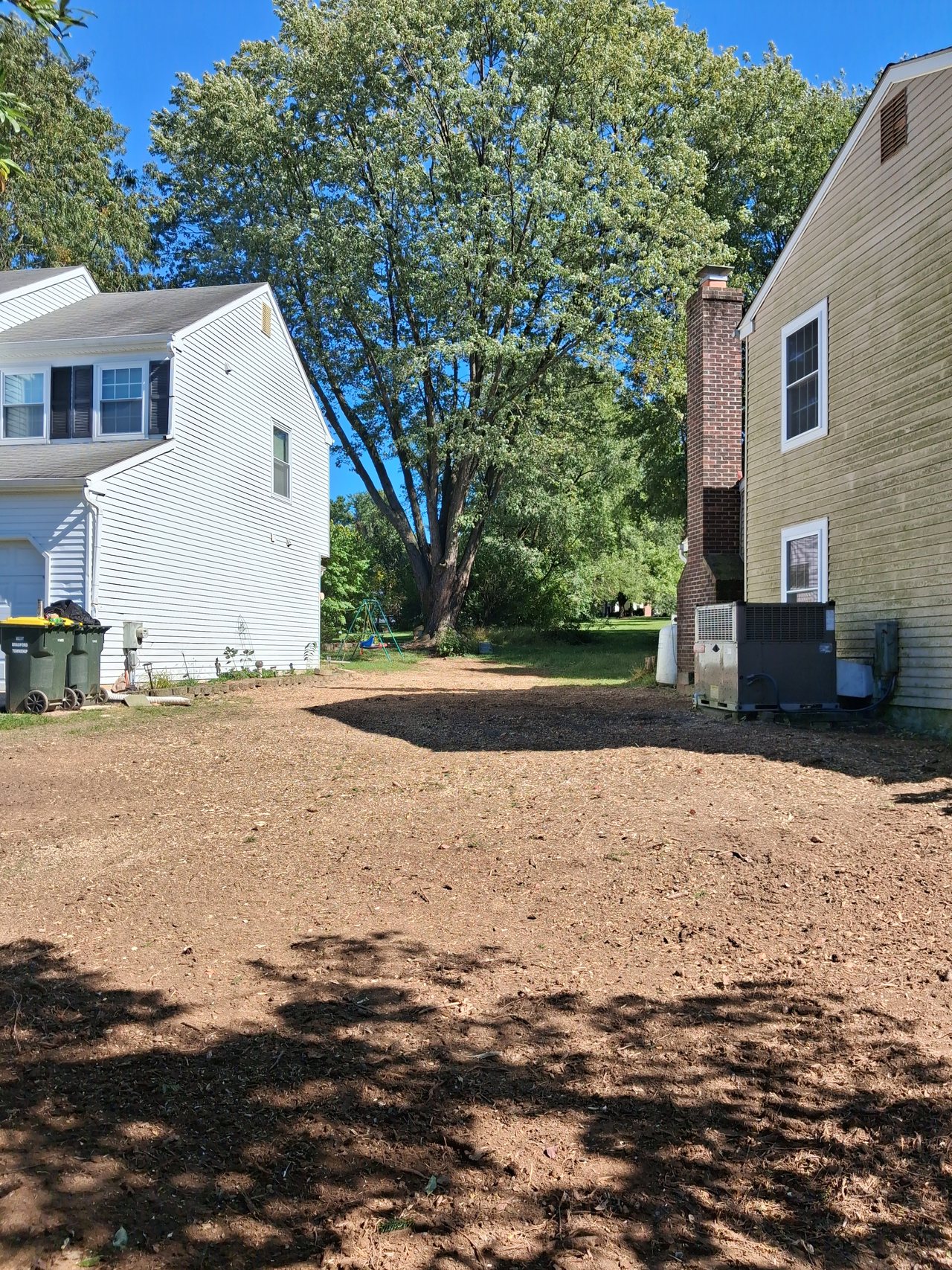 Ground between two houses cleared and raked level after a pine removal